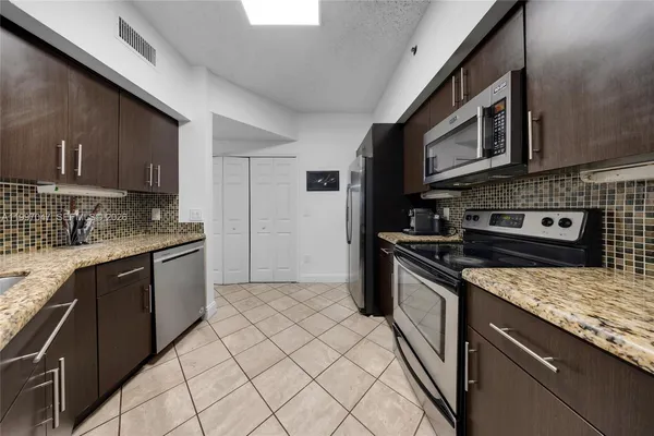 a kitchen with stainless steel appliances granite countertop a stove microwave and sink
