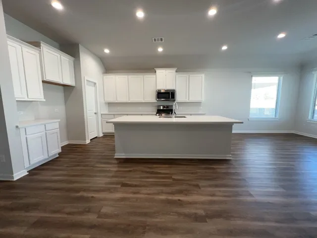 a view of kitchen with kitchen island a sink wooden floor and white stainless steel appliances