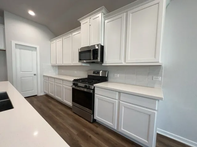 a kitchen with white cabinets and stainless steel appliances