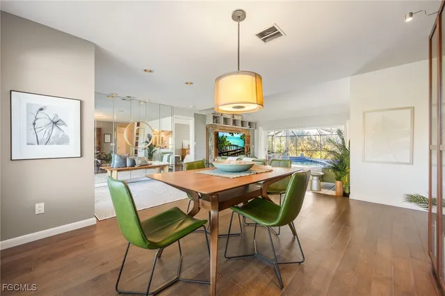 a dining room with wooden floor a chandelier a wooden table and chairs
