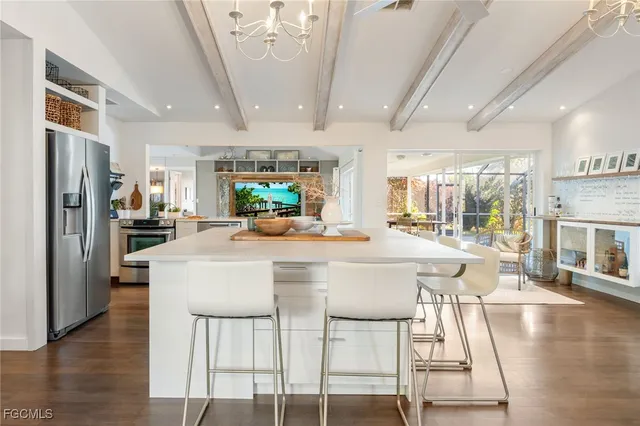 a kitchen with stainless steel appliances a dining table chairs refrigerator and sink