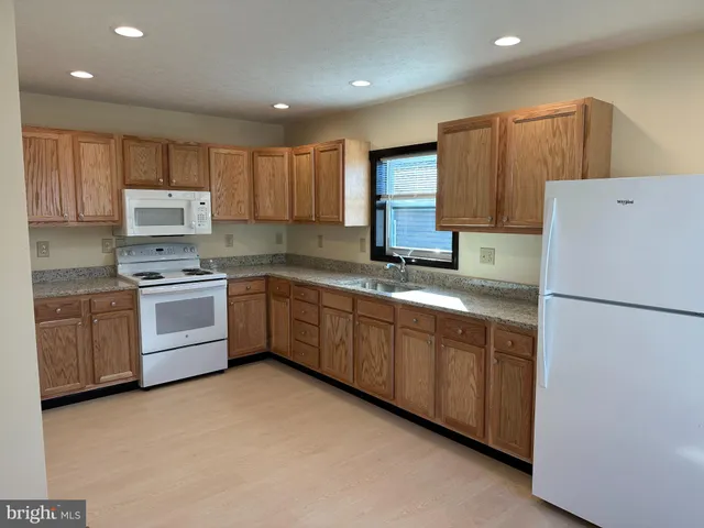 a kitchen with a white refrigerator oven a sink dishwasher and white cabinets