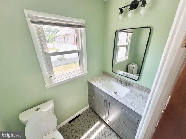 a bathroom with a granite countertop toilet sink and mirror