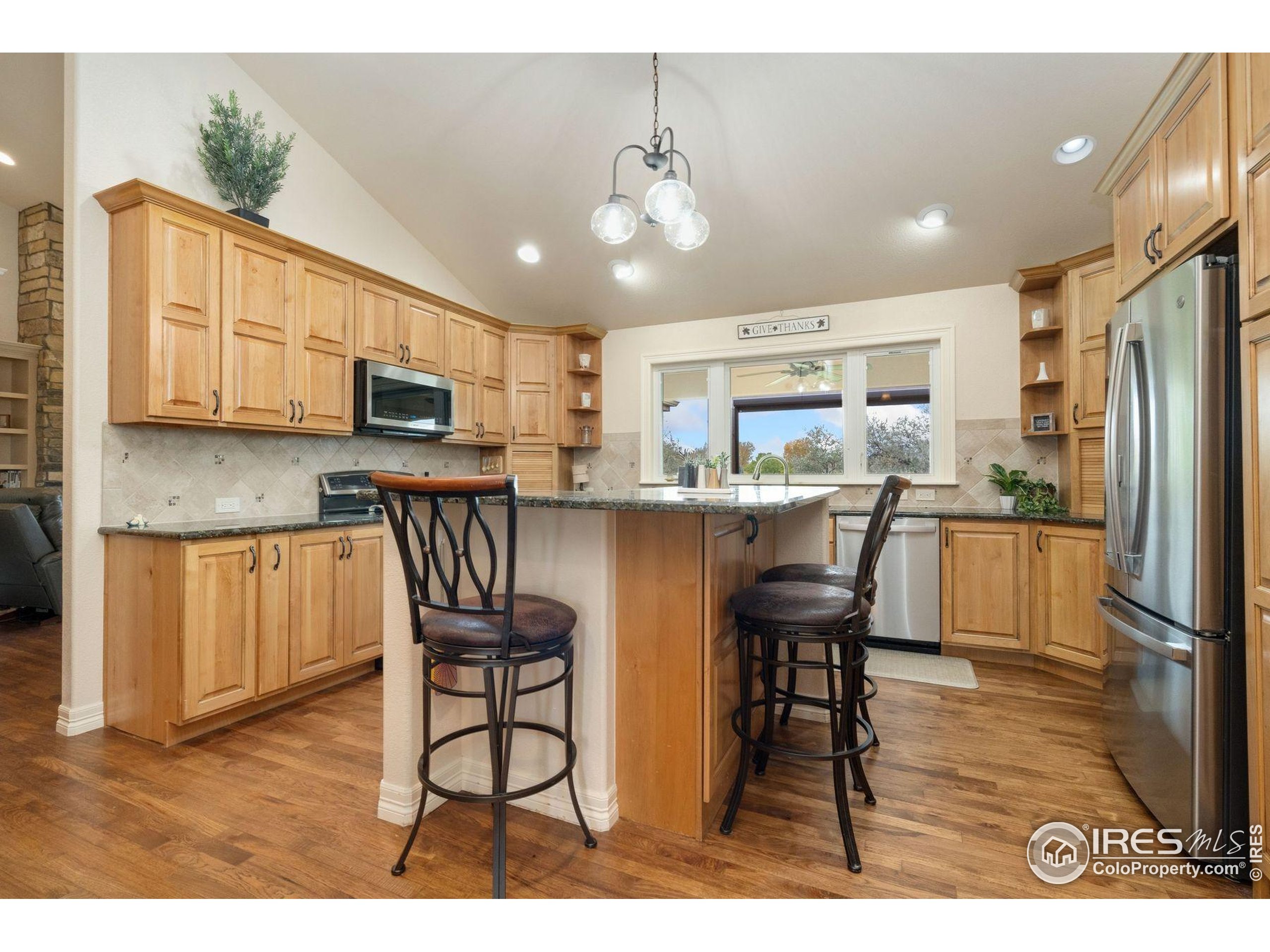 1055 Coho Run Fort Collins, CO 80524 - Photo 33 of 50 a kitchen with stainless steel appliances kitchen island granite countertop a refrigerator a stove a sink dishwasher with a dining table and chairs