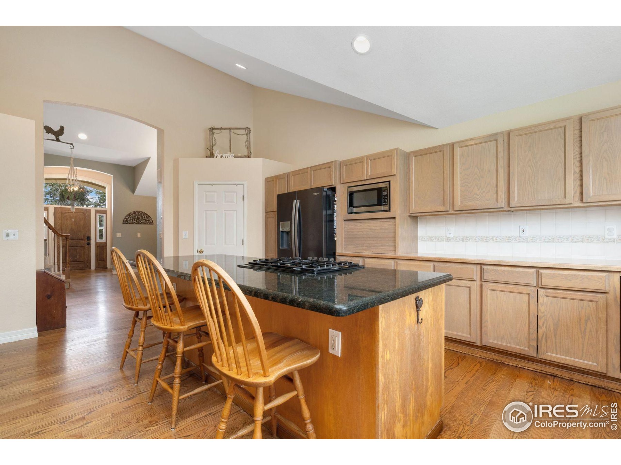 1055 Coho Run Fort Collins, CO 80524 - Photo 5 of 50 a kitchen with stainless steel appliances granite countertop a stove top oven a sink dishwasher and white cabinets with wooden floor