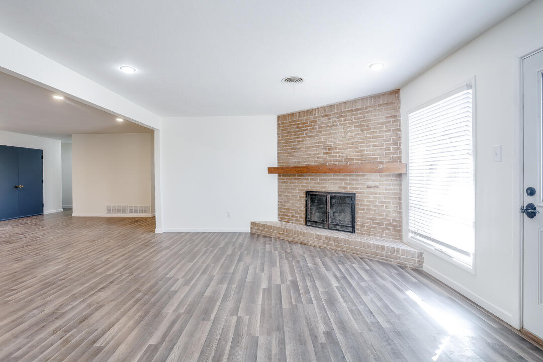 2123 66th Street Lubbock, TX 79412 - Photo 7 of 16 an empty room with wooden floor fireplace and windows