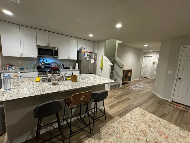 a kitchen with stainless steel appliances granite countertop a sink counter space and wooden floor