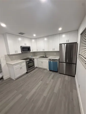 a large kitchen with cabinets wooden floor and stainless steel appliances