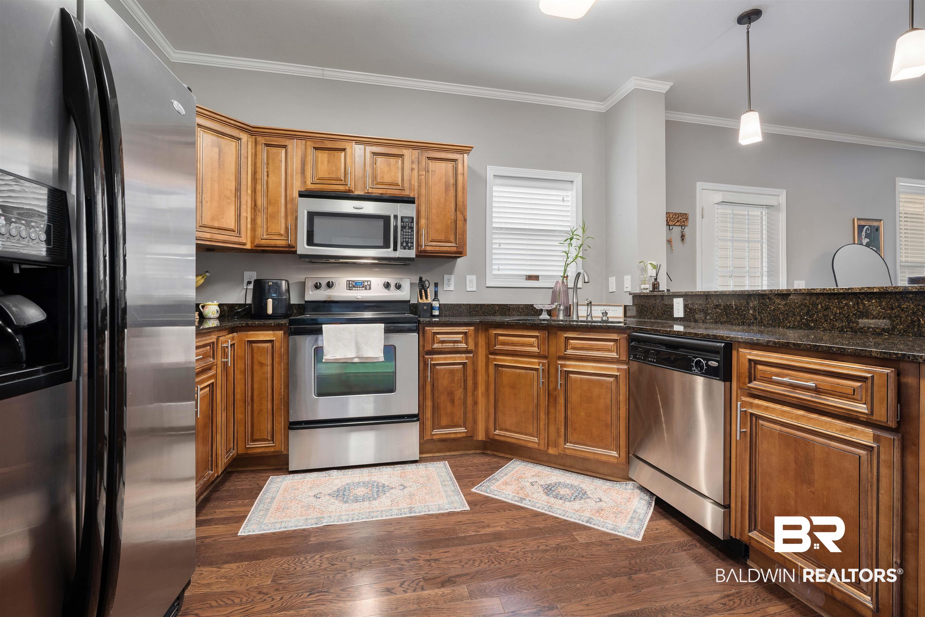 25806 Pollard Road, Unit 205 Daphne, AL 36526 - Photo 3 of 26 Kitchen with stainless steel appliances, wood finish cabinetry, crown molding, dark stone countertops, and decorative light fixtures