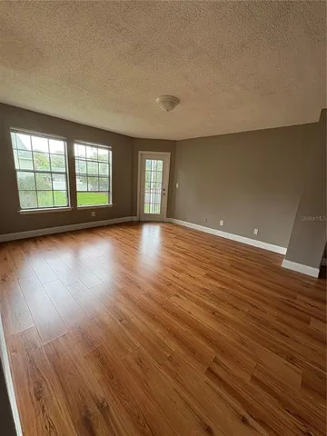 a view of an empty room with wooden floor and window
