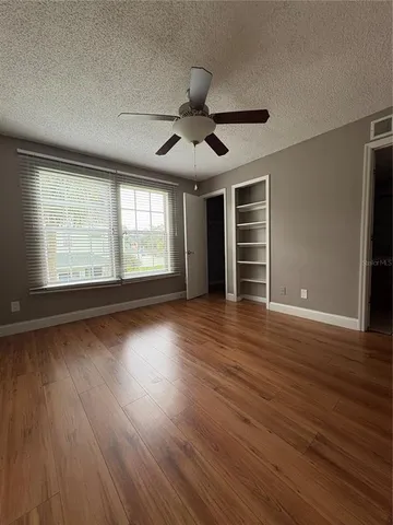 a view of empty room with wooden floor and fan