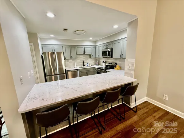 a kitchen with stainless steel appliances a dining table chairs and refrigerator