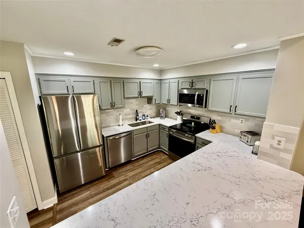 a kitchen with refrigerator a microwave a sink and cabinets