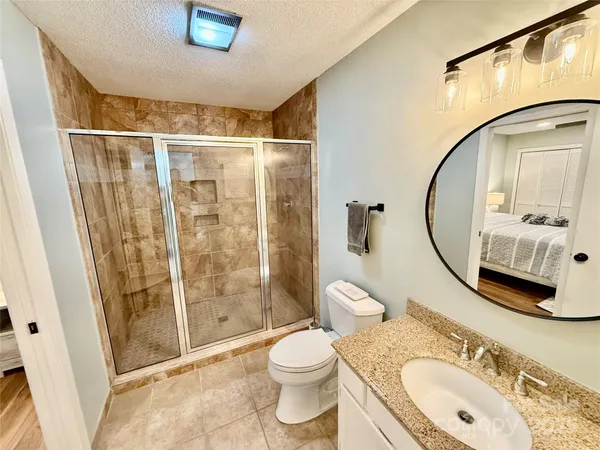 a bathroom with a granite countertop sink toilet and shower
