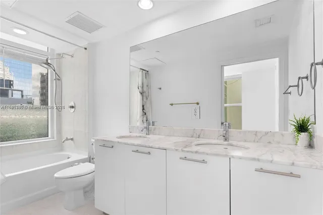 a bathroom with a granite countertop sink toilet a large mirror a bathtub and shower