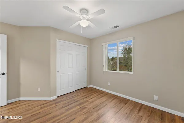 a view of an empty room with a window and wooden floor