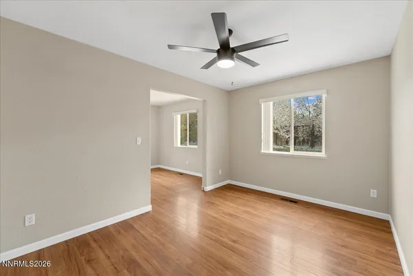 a view of an empty room with wooden floor and a window