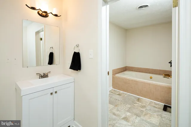 a bathroom with a tub sink and mirror