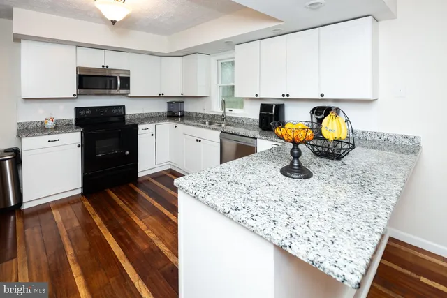 a kitchen with stainless steel appliances granite countertop a sink stove and microwave