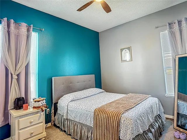 a bedroom with a large bed a flat tv screen and a chandelier
