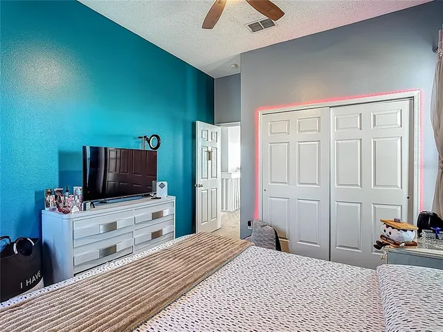 a spacious bedroom with a bed and a ceiling fan