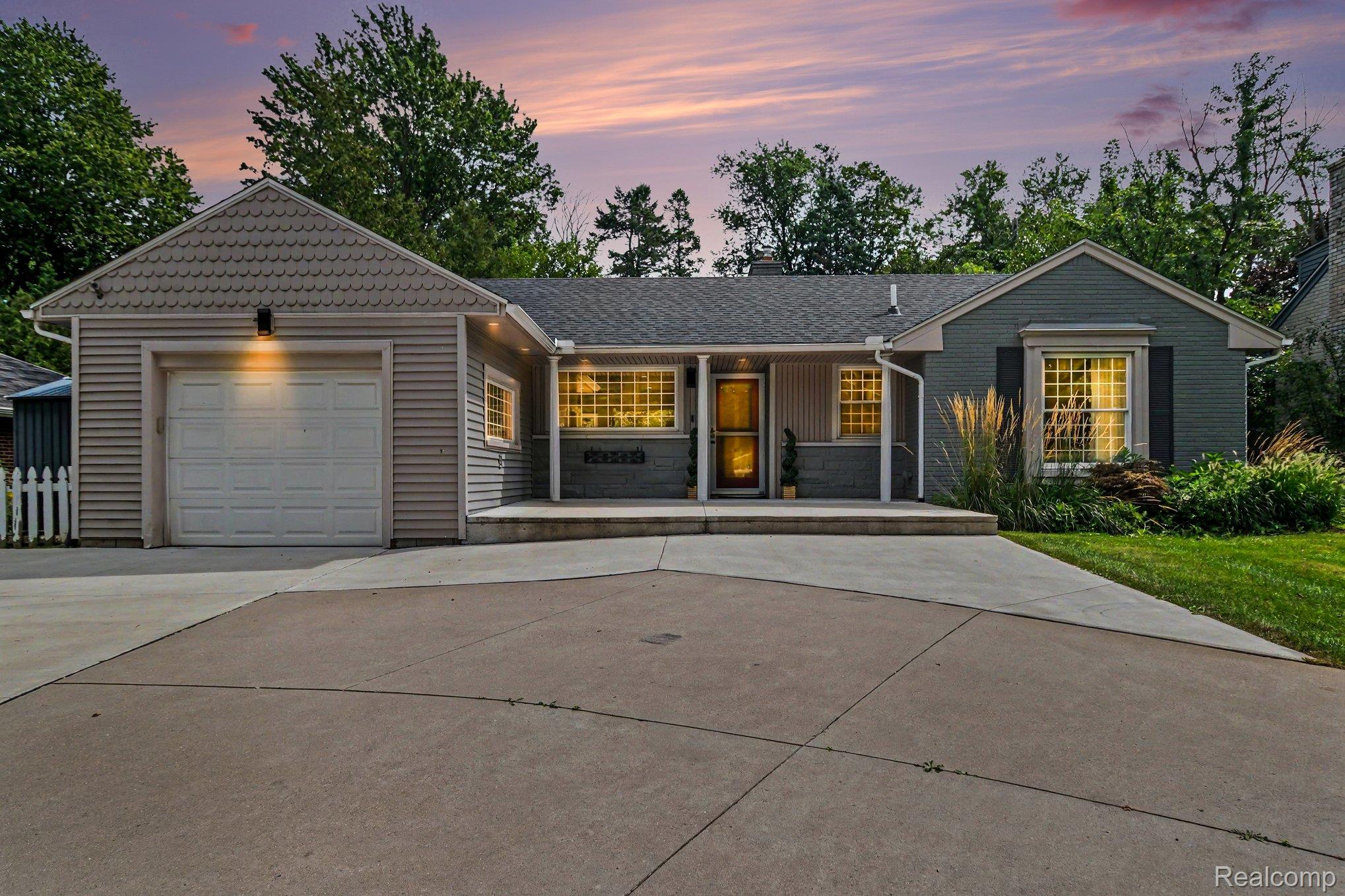 Gray siding exterior with a single-car garage, concrete driveway, and front porch