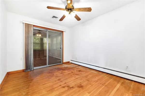 an empty room with windows and fan