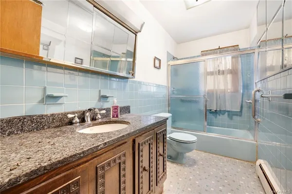 a bathroom with a granite countertop sink a toilet a mirror and shower