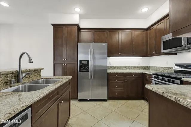 a kitchen with stainless steel appliances granite countertop a sink stove and refrigerator