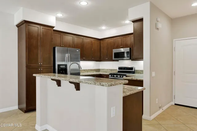 a kitchen with stainless steel appliances granite countertop a stove a refrigerator and a microwave