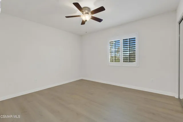 an empty room with a window and a ceiling fan