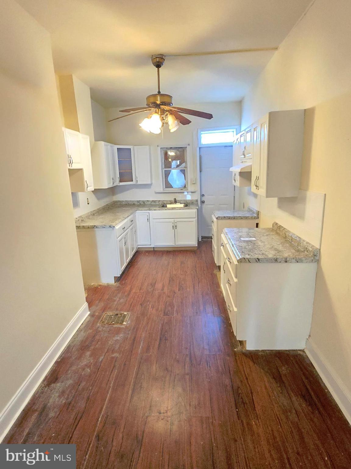 321 South Mount Street Baltimore, MD 21223 - Photo 6 of 20 a large kitchen with cabinets wooden floor and stainless steel appliances
