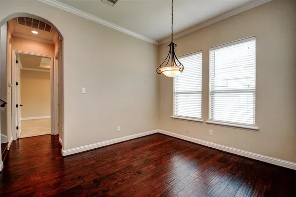 an empty room with wooden floor chandelier and windows