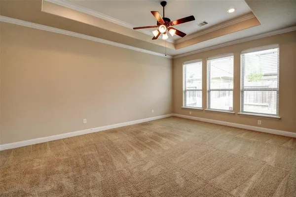 an empty room with chandelier fan and windows