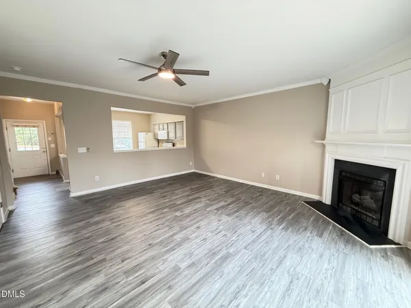 an empty room with wooden floor fireplace and windows