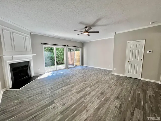 a view of an empty room with wooden floor fireplace and a window