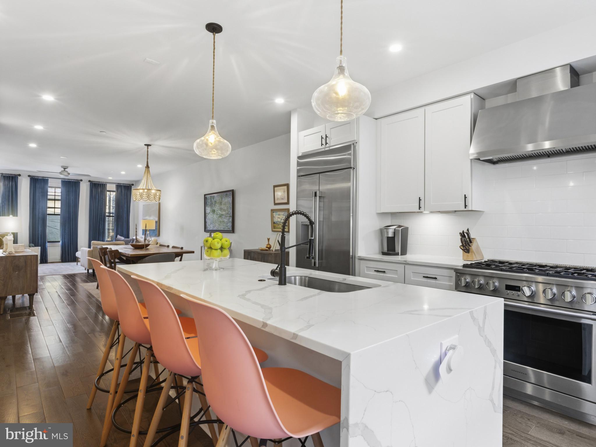 1404 Olive Street Baltimore, MD 21230 - Photo 7 of 38 a kitchen with stainless steel appliances granite countertop a stove a sink a microwave a refrigerator a stove a dining table and chairs with wooden floor