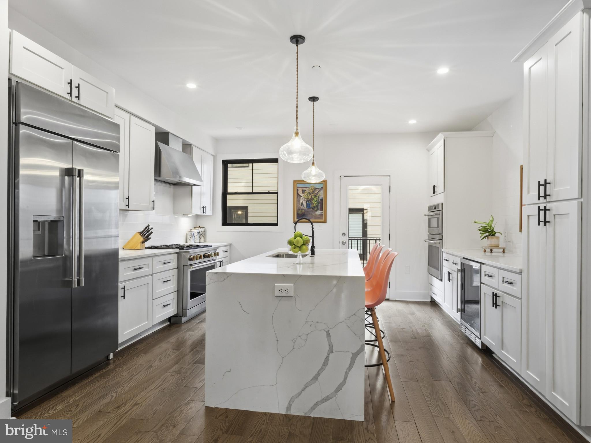 1404 Olive Street Baltimore, MD 21230 - Photo 8 of 38 a kitchen with stainless steel appliances a stove a refrigerator a oven a sink dishwasher and white cabinets with wooden floor