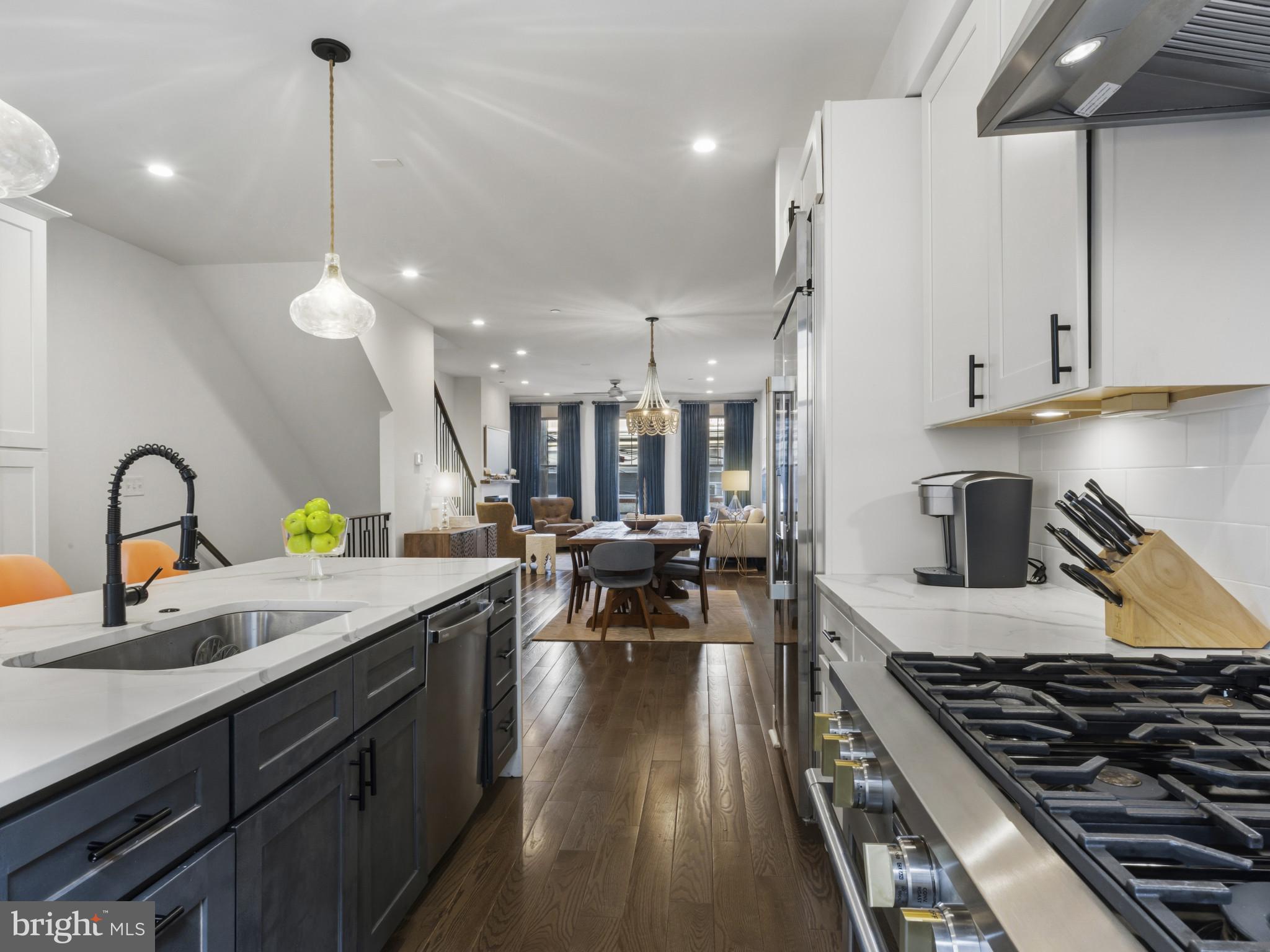 1404 Olive Street Baltimore, MD 21230 - Photo 10 of 38 a kitchen with kitchen island granite countertop a stove a sink a dining table and chairs with wooden floor