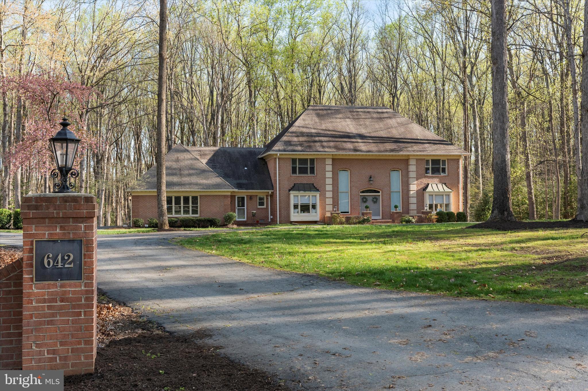 a front view of a house with a garden and trees
