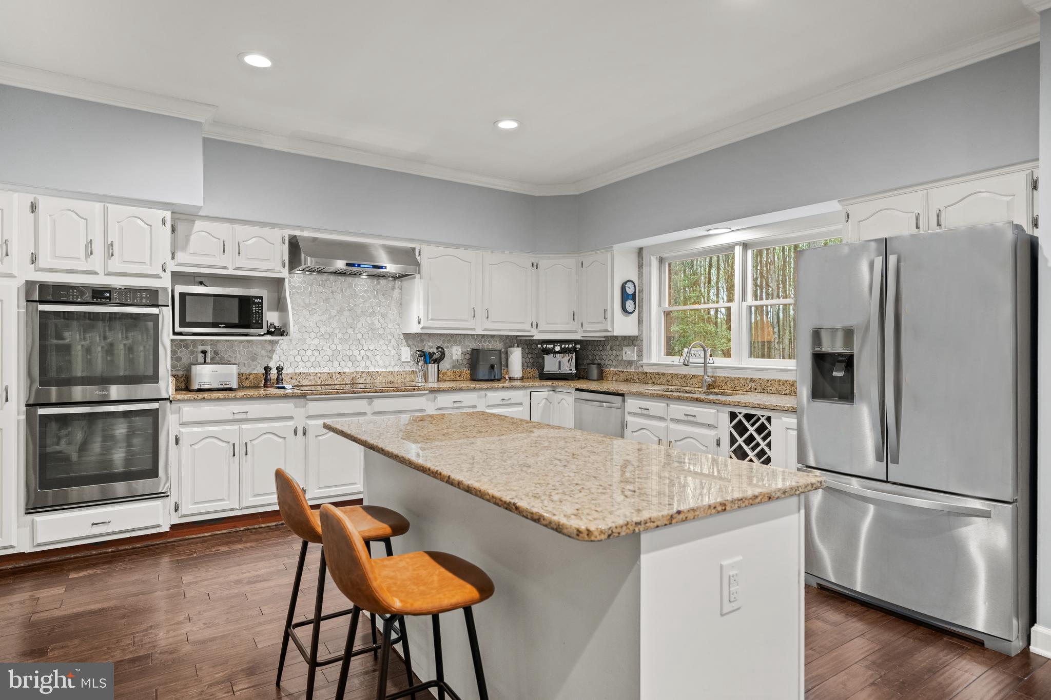 642 Springvale Road Great Falls, VA 22066 - Photo 9 of 50 a kitchen with stainless steel appliances granite countertop a stove a sink a refrigerator and white cabinets with wooden floor