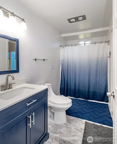 a bathroom with a sink a toilet a mirror and shower curtain