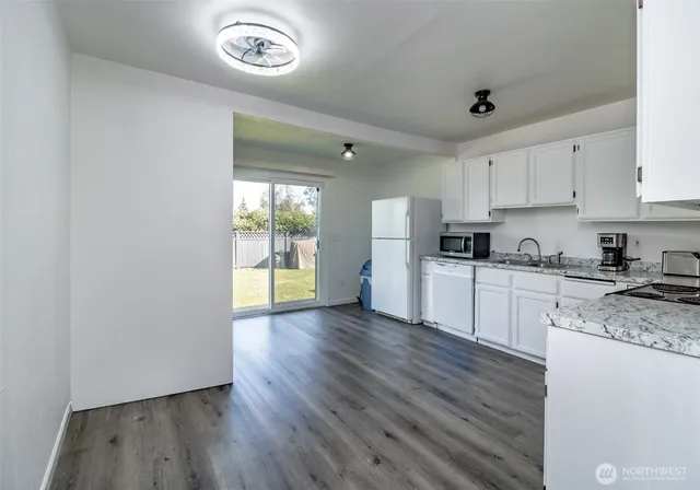 a kitchen with granite countertop a stove a sink and a microwave