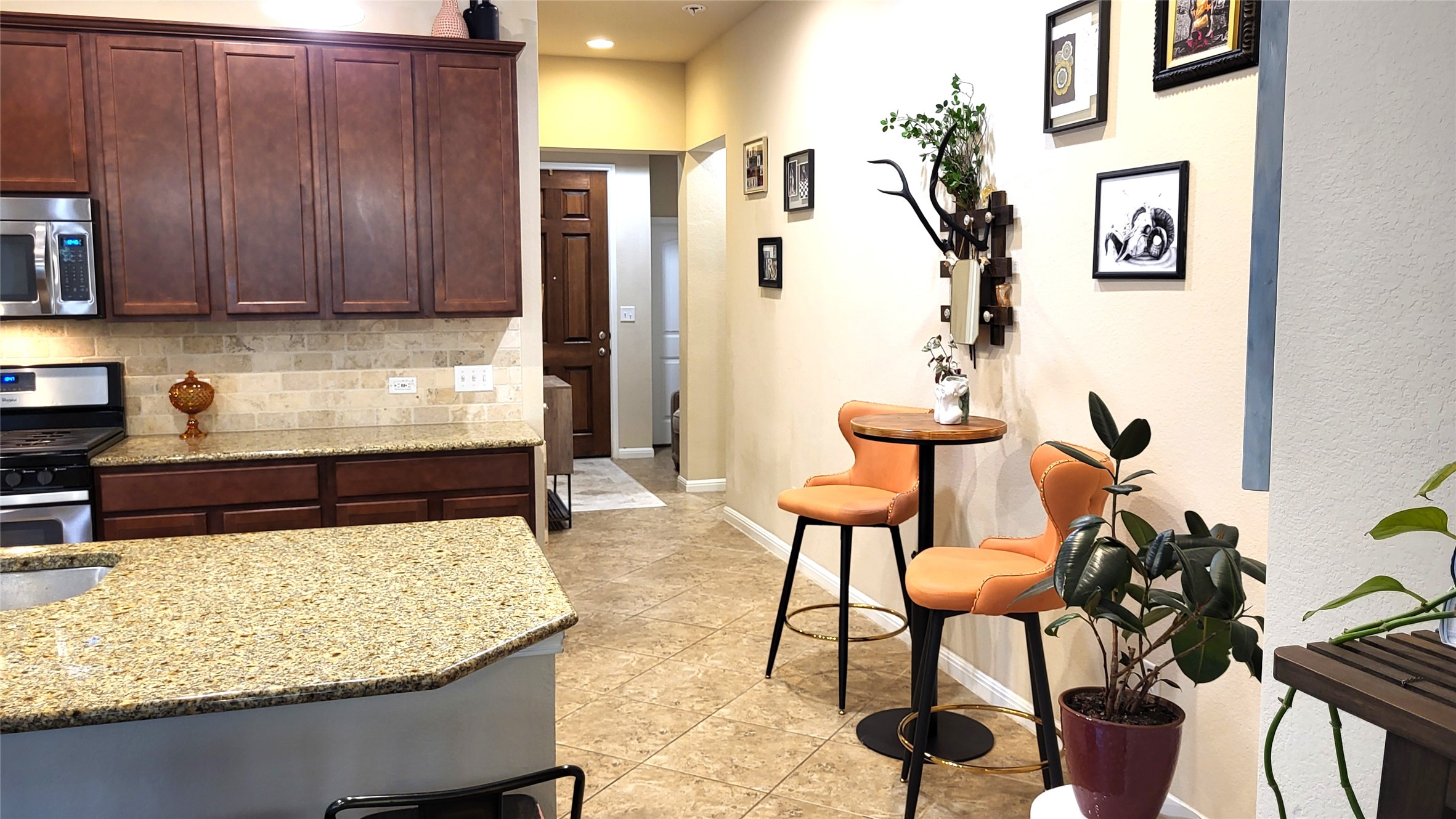 413 Anacua Loop, Unit 8 Manchaca, TX 78652 - Photo 3 of 23 Rich wood cabinetry and polished granite counters anchor this kitchen with a natural stone tile backsplash.