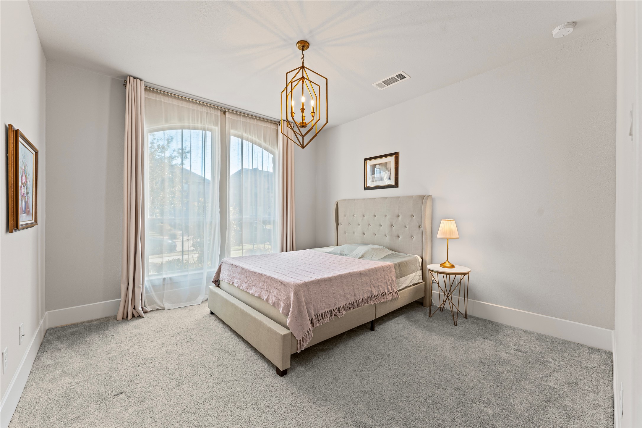 8815 Iron Forge Road Missouri City, TX 77459 - Photo 23 of 40 a spacious bedroom with a bed a window and a chandelier