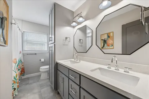 a bathroom with a double vanity sink mirror and toilet