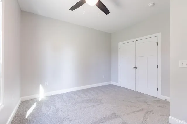 an empty room with ceiling fan and window