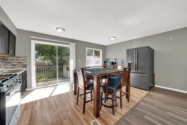 a kitchen with granite countertop a dining table chairs and refrigerator