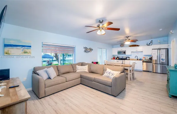 a living room with furniture kitchen view and a chandelier