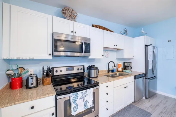 a kitchen with stainless steel appliances granite countertop a stove a sink dishwasher and a refrigerator with wooden cabinets
